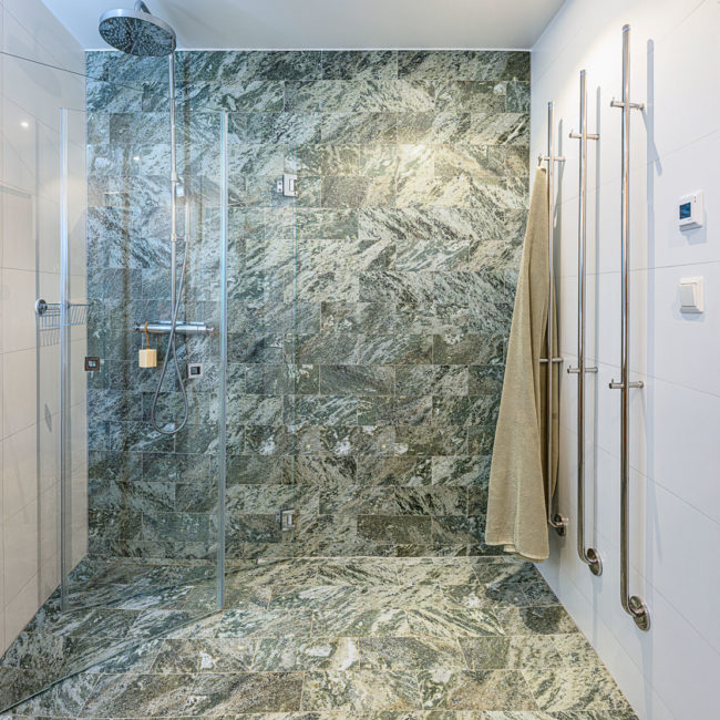 Renoverat badrum med dusch - grönt klinkers som går upp över ena väggen i duschen